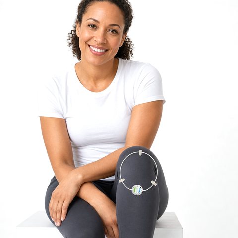 Smiling woman wearing an ActiPatch® loop and control unit taped over thin leggings on her right knee